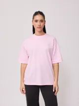 Remera de corte oversized, color amarillo, con cuello redondo y mangas cortas. Presenta un estampado gráfico pequeño en la parte inferior delantera.