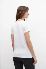 Remera blanca de algodón con cuello redondo y strass plateados formando pequeños dibujos.