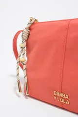 Bolso bandolera mini de Bimba y Lola en color negro, con cierre de cremallera superior, asas cortas de mano y tirador decorativo de cuerda con cuentas rojas. Presenta el logotipo de la marca impreso en letras doradas en la parte frontal.