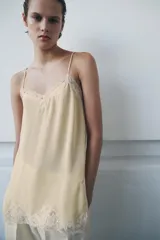 Top lencero de escote en pico y tirantes finos ajustables, confeccionado en tejido fluido con aplicaciones de encaje a tono en el escote y el bajo.
