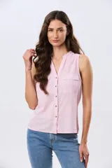 Musculosa de lino color beige, con cuello mao y escote en V, cierre frontal con botones y dos bolsillos plaqué con solapa en el pecho.