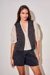 Chaleco sin mangas de corte al cuerpo, color negro con bordados florales en hilo contrastante. Presenta un diseño abierto con terminaciones reforzadas.