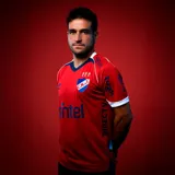 Camiseta de fútbol Umbro del Club Nacional de Football, modelo Away 2025. Diseño en color rojo con detalles en azul y blanco en el cuello y los puños. Incluye el escudo del club, el logo de Umbro y los patrocinadores estampados en el frente y las mangas.