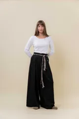 Pantalón wide leg de tiro alto en color negro, con diseño de pinzas delanteras que aportan volumen y caída fluida. Incluye bolsillos laterales y un lazo desmontable en la cintura que combina cordón con cinta de estampado animal print.