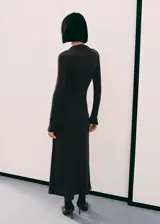 Vestido largo de punto color gris oscuro, con cuello perkins y manga larga. Presenta un diseño entallado con detalle fruncido en la cintura y una anilla metálica decorativa.