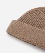 Gorro tipo fisherman de tejido acrílico con textura acanalada, diseño corto y etiqueta pequeña con logo en el frente.