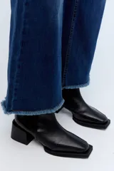 Jean de pierna ancha, tiro alto, color azul oscuro con desgaste en los muslos y ruedo desflecado.