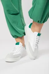 Zapatillas acordonadas de cuero color blanco con puntera de gamuza gris y detalles en verde.