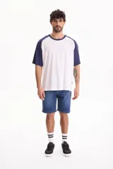 Remera oversize de manga corta raglán, color blanco con mangas y cuello en azul marino.