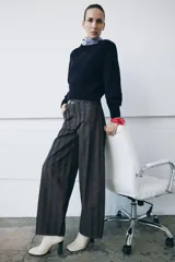Jeans de tiro medio con corte barrel leg, confeccionados en denim con rayas verticales a contraste en tonos azul oscuro y marrón/tostado. Presentan cinco bolsillos y cierre frontal con cremallera y botón.