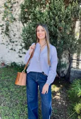 Blusa celeste a rayas verticales blancas, de corte holgado, con cuello mao y mangas largas abullonadas con puños elásticos.