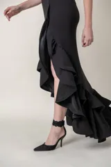 Vestido largo negro de crepe con spandex, corte recto con tajo alto y volados en el ruedo.