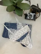 Conjunto de lencería compuesto por un top bralette de encaje floral con breteles regulables y una tanga colaless a juego con tiras laterales ajustables.
