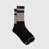 Par de medias de caña alta con diseño color block en negro y beige, con detalle de rayas horizontales blancas y negras en la parte superior y texto bordado.