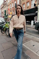 Campera bomber color beige, de cuello redondo y manga larga. Tiene bolsillos delanteros y bajo acabado en elástico. Cierre frontal con cremallera.