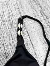 Malla entera negra con escote en V, breteles finos con detalle de caracoles y espalda cruzada.