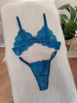 Conjunto de lencería de encaje floral color verde petróleo, compuesto por un corpiño triangular sin aro y una bombacha tipo colaless con tiras laterales ajustables.