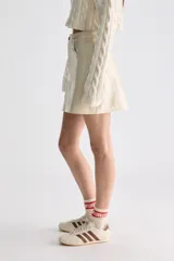 Minifalda evasé de tiro alto, confeccionada en material sintético de acabado brillante, estilo charol, con diseño de cinco bolsillos y cierre frontal con botón y cremallera.