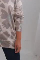 Sweter de punto amplio con escote en V y mangas largas. Presenta un estampado floral estilo acuarela en tonos neutros.