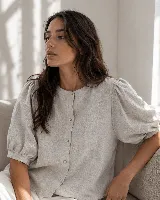 Blusa de lino color gris claro con bordados de pequeñas ramas en tono ocre. Presenta cuello redondo, cartera oculta con botones de nácar y mangas largas con puños estructurados con tablas.