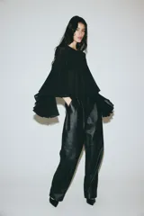 Blusa corta de tejido liviano con diseño oversized, escote redondo y mangas largas acampanadas con volados. Presenta costura fruncida en el pecho que aporta volumen y abertura en V en la espalda.
