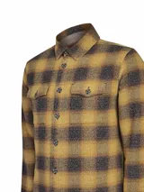 Chaqueta tipo overshirt de algodón con diseño a cuadros en tonos ocre y gris oscuro. Presenta cuello clásico, cierre frontal abotonado y dos bolsillos con solapa en el pecho.
