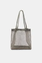 Bolso tipo tote cuadrado, confeccionado en tejido de malla metálica semitransparente. Cuenta con dos asas superiores fijas y detalles de remaches metálicos en la unión de las asas con el cuerpo del bolso.