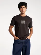 Camiseta blanca de algodón con cuello redondo y mangas cortas. Estampa rectangular con borde negro que contiene la frase "NATURAL ATMOSPHERE" en letras mayúsculas y una imagen de montañas y mar.