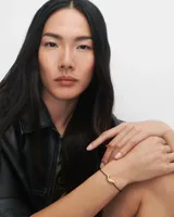 Pulsera PD Paola con cordón negro y dije dorado en forma de flecha.