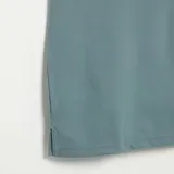 Remera tipo chomba de manga corta con textura de nido de abeja, color azul, cuello polo y cierre frontal parcial de cremallera.
