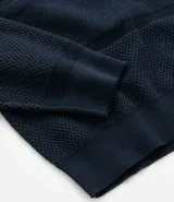 Buzo azul marino de algodón texturizado, con cuello redondo y mangas largas con puños ajustados.