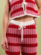 Pantalón acampanado tejido en algodón a rayas horizontales rojas y rosadas, con cintura elastizada y cordón de ajuste.