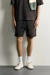 Bermuda estilo jogger de ajuste relajado, confeccionada en tejido interlock de algodón. Cuenta con cintura elástica ajustable con cordón, bolsillos frontales de vivo y diseño liso.