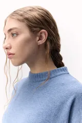 Sweater de lana color crema, de cuello alto y corte holgado.