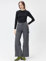 Pantalón de tiro medio y pierna ancha confeccionado en denim de algodón grueso. Presenta un diseño a rayas verticales en tonos azul y celeste, con costuras en contraste color rojo, bolsillos laterales tipo cargo y remaches metálicos.