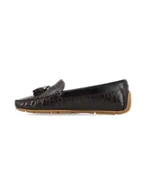 Mocasín de cuero con textura tipo cocodrilo en color marrón chocolate, con detalle de borlas y herraje metálico en el empeine, y suela de goma color caramelo.