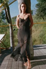 Vestido midi de tirantes finos con escote en pico, confeccionado en viscosa con estampado de lunares. Presenta aplicaciones de encaje en el escote y en la falda, con un bajo de acabado asimétrico.