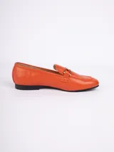 Mocasines color naranja de símil cuero con aplique metálico dorado en la parte superior, plantilla acolchada y taco de 1,5cm.