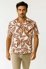 Camisa de manga corta con cuello tipo cubano, confeccionada en viscosa con estampado botánico de hojas en tonos marrones sobre fondo crema.
