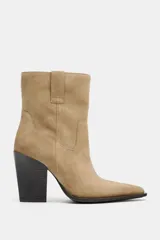Botín de piel estilo cowboy en color beige, con detalle de pespuntes en el cuerpo, tiradores laterales y tacón alto en bloque.