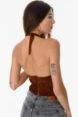 Top marrón de cuero descarne, con cuello halter ajustable con hebilla, escote pronunciado y cierre frontal con cordones.