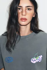 Camiseta de algodón con efecto lavado, corte oversize, cuello redondo y manga corta. Presenta estampados gráficos en el frente.