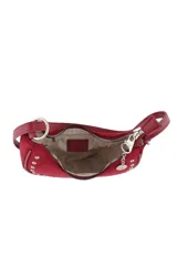 Cartera tipo bandolera de diseño semicircular, confeccionada en material con textura gamuzada color bordó. Presenta detalles de tachas metálicas plateadas en todo el contorno, cierre superior con tirador decorado con un dije metálico circular y correa larga ajustable.