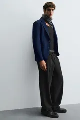 Blazer azul marino de corte recto, confeccionada en tejido con viscosa. Tiene cuello con solapas de muesca, manga larga con puño abotonado, bolsillo de vivo en el pecho y bolsillos de parche en la cadera. El bajo tiene aberturas en la espalda y el cierre es con botonadura frontal.