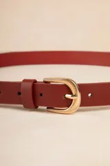 Cinturón color beige de cuero sintético con hebilla dorada texturizada.