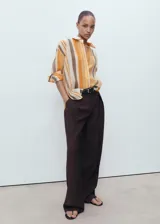 Camisa de lyocell con estampado de rayas verticales en tonos naranja, marrón y beige. Tiene cuello camisero, manga larga con puños abotonados y cierre frontal con botones.