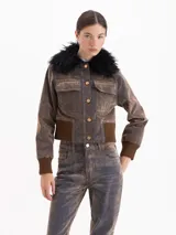 Campera estilo bomber de silueta entallada, confeccionada en tela Denim Velvet con acabado visual de jean y tacto de terciopelo. Presenta cuello desmontable de pelo sintético, cierre frontal con botones, bolsillos superiores y puños y cintura de tejido elástico acanalado.