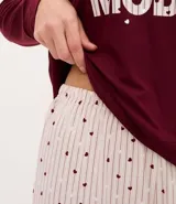 Pijama largo compuesto por una blusa de manga larga en color bordó con estampado frontal de texto y un pantalón con cintura elástica y estampado de lunares.