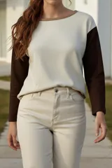 Sweater de punto color blanco con mangas largas color marrón y cuello redondo con borde marrón.