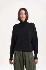 Polera de lana de corte holgado, con cuello alto tejido y mangas largas con caída de hombro.